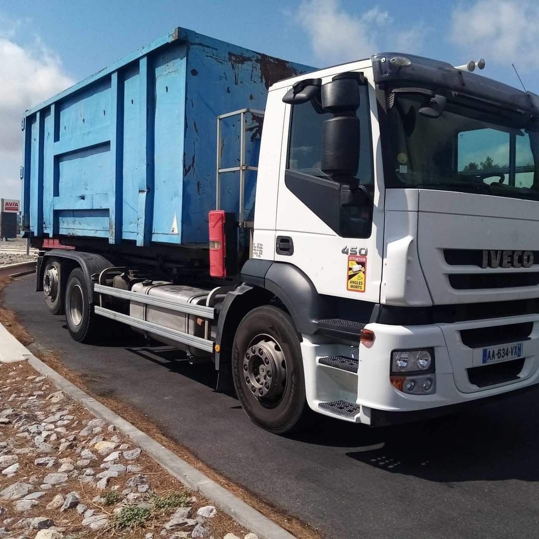 Camion-benne bleu stationné en bord de route.