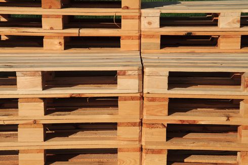 Gros plan de palettes en bois empilées aux lattes aux tons chauds.