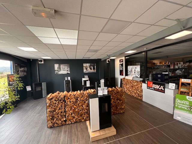 Intérieur d'une salle d'exposition de poêles à bois, murs sombres et comptoir recouvert de bois.