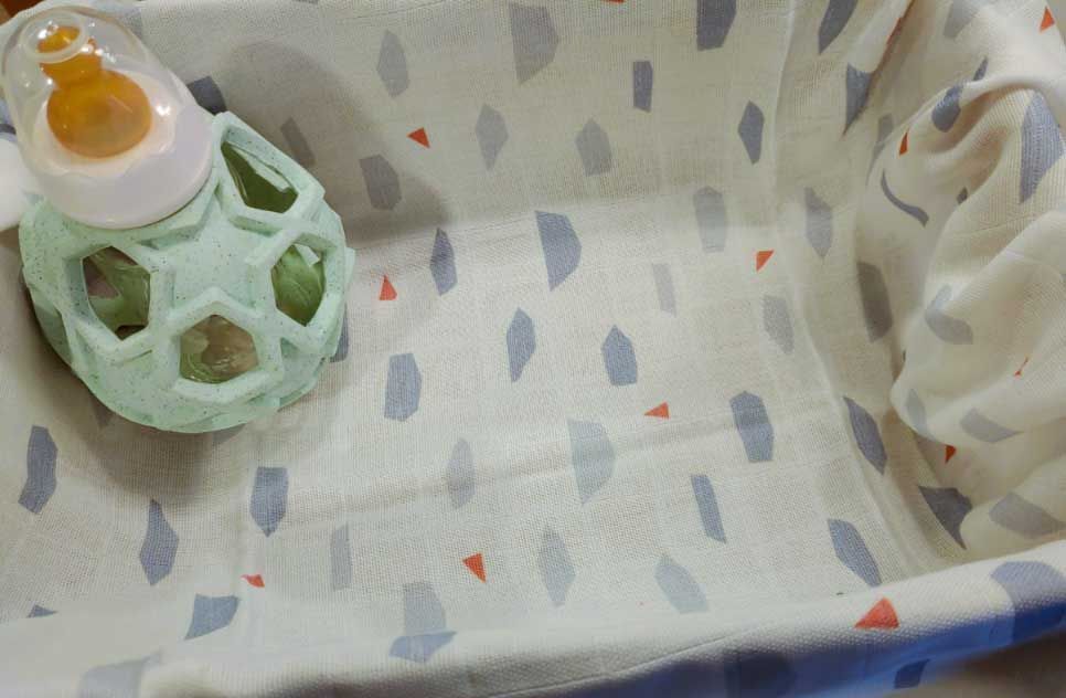 Eine Babyflasche mit runder Form steht in einem leeren Kinderbett.