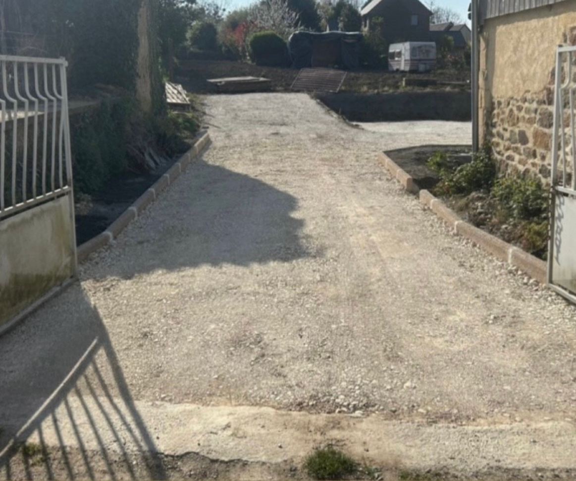 Un chemin de terre menant à une maison avec une clôture en arrière-plan.