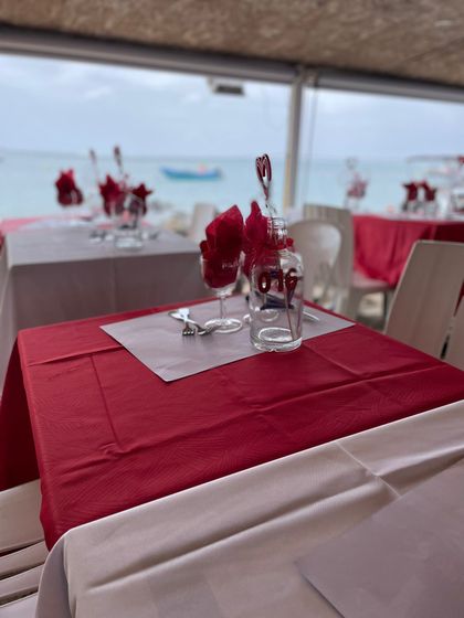 Restaurant aux tables rouges au bord de l'océan. Tables dressées avec verres et serviettes rouges.