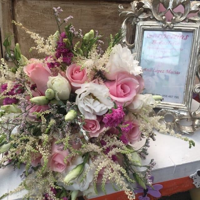 Arreglo floral rosa y blanco junto a una foto conmemorativa enmarcada y ornamentada sobre una mesa