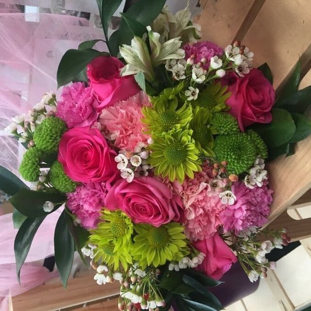 Un ramo vibrante de flores rosas y verdes, con rosas y detalles blancos