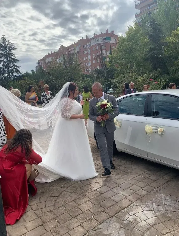 La novia y el novio están junto a un coche blanco decorado en una ceremonia de boda al aire libre