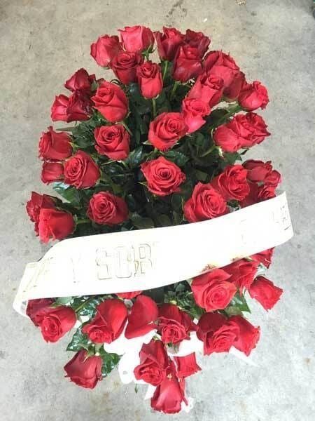 Ramo de rosas rojas con una cinta blanca sobre una superficie gris