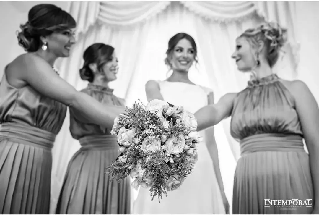Novia con tres damas de honor sosteniendo ramos de flores durante una ceremonia de boda