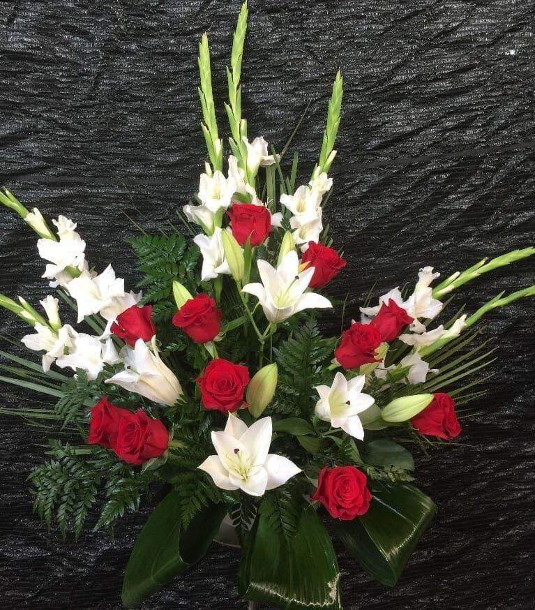 Rosas rojas y lirios blancos dispuestos en un ramo sobre un fondo negro texturizado