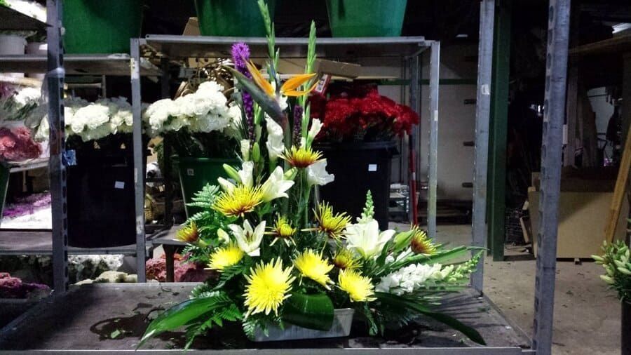 Arreglo floral con flores amarillas, blancas y moradas en el escaparate de una tienda