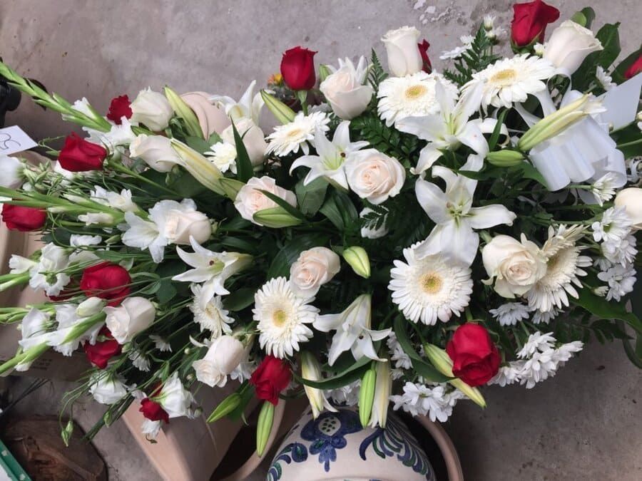 Arreglo floral blanco y rojo en un jarrón azul sobre un suelo de baldosas