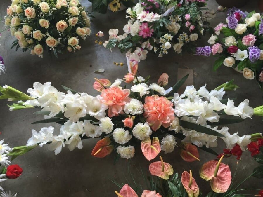 Arreglo floral con flores blancas, melocotón, rosas y moradas sobre una superficie oscura