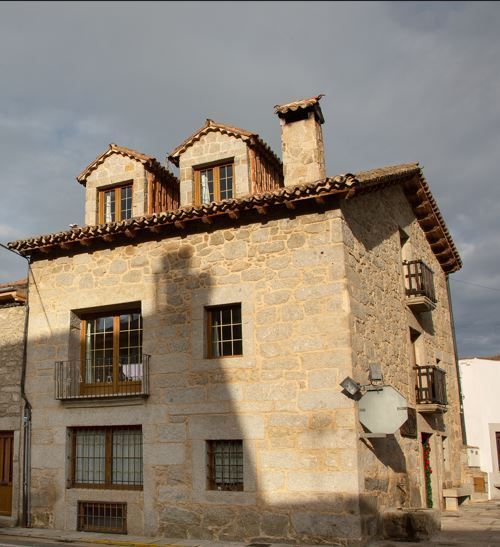 Casa de piedra de varios pisos, buhardillas y balcones.