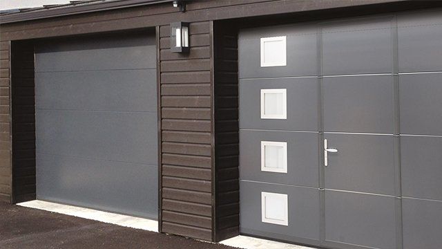 Porte de garage sectionnelle verticale et façade avec bardage en bois foncé