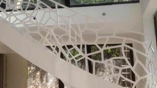 Escalier design avec garde-corps en fer forgé travaillé blanc, traversant l'intérieur d'une maison d'architecte
