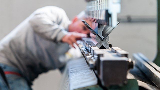 Focus sur une machine pliant une pièce d'acier à l'angle