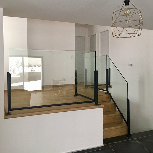 Garde-corps en verre séparant deux niveaux et escalier en bois