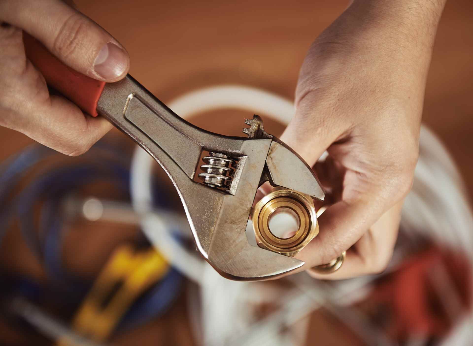 Handwerker schraubt einen Anschluss an einen Schlauch