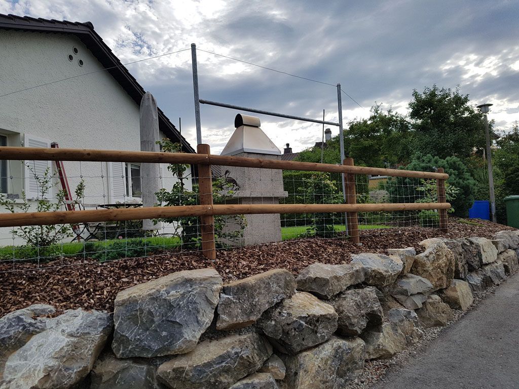 Natursteinmauer mit Holzzaun - Hadorn Gartenbau