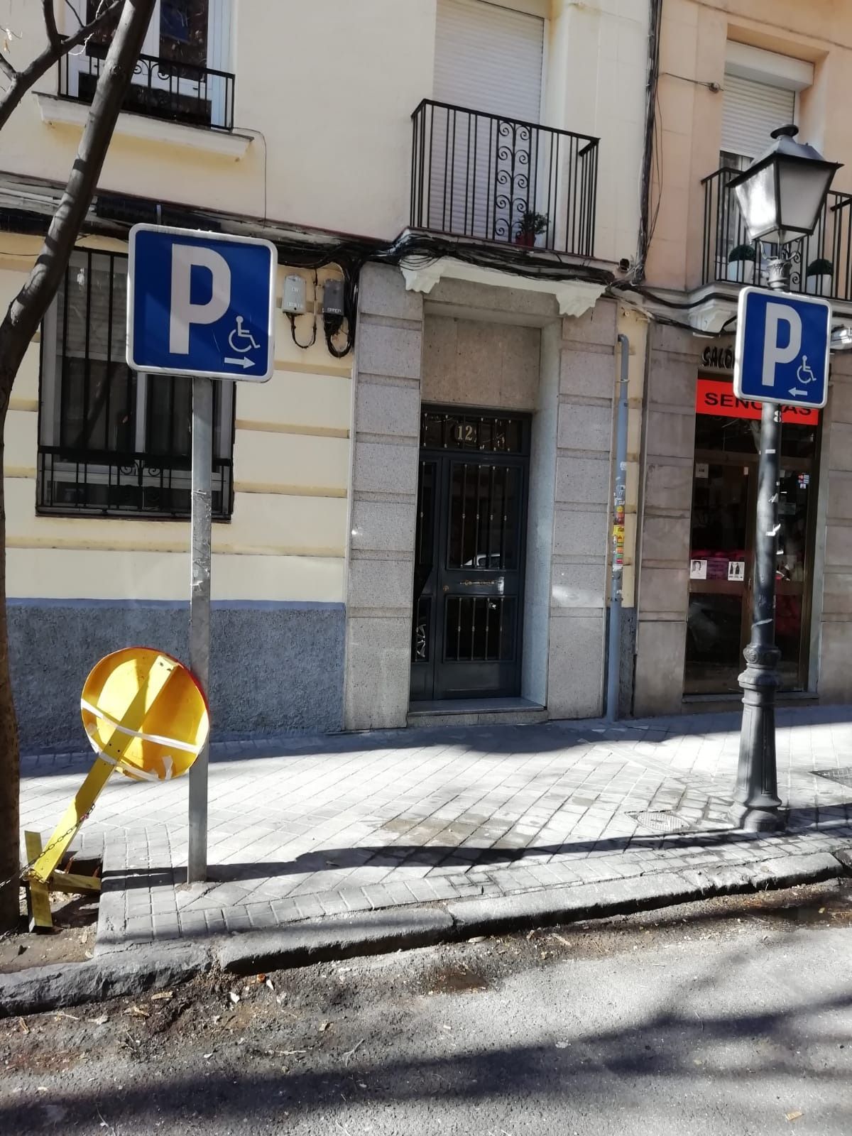 Hay una señal de estacionamiento para discapacitados en la acera frente a un edificio.