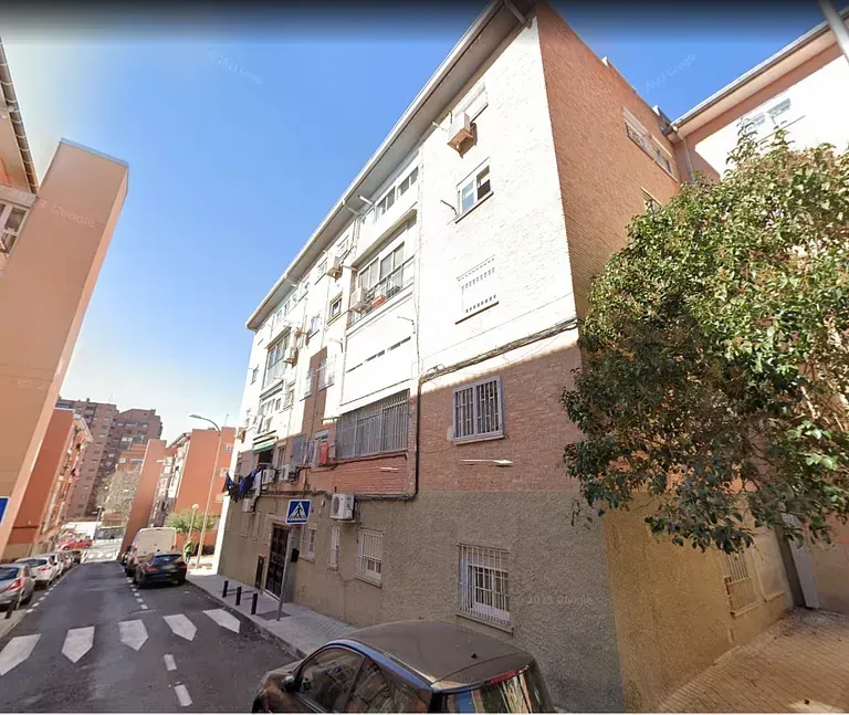 Un edificio de ladrillo con un coche aparcado delante.