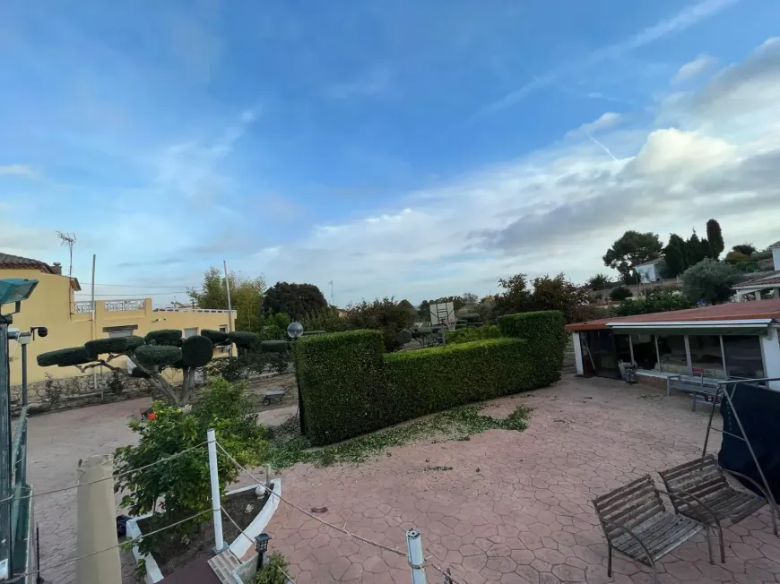 Una vista panorámica de un patio residencial con un seto bien recortado y suelo de grava.