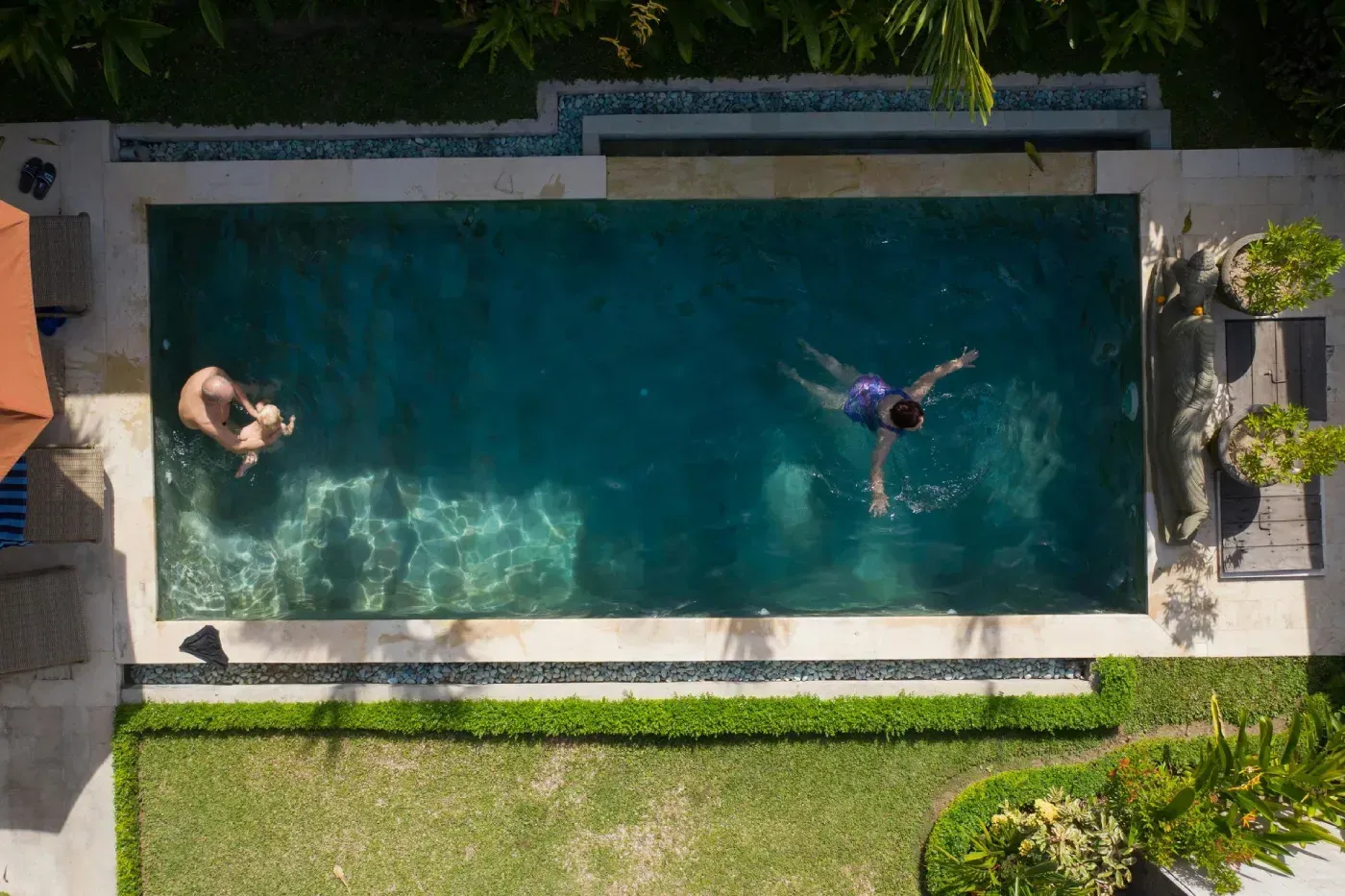 Vista aérea de dos personas nadando en una piscina rectangular al aire.