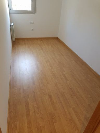 Una habitación vacía con suelo de madera y paredes blancas.