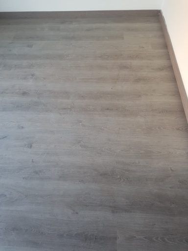 Un primer plano de un piso de madera gris en una habitación.