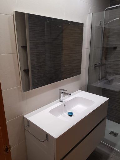 Un baño con lavabo, espejo y ducha.