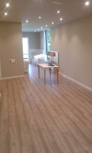 Una gran habitación vacía con suelo de madera y una mesa.