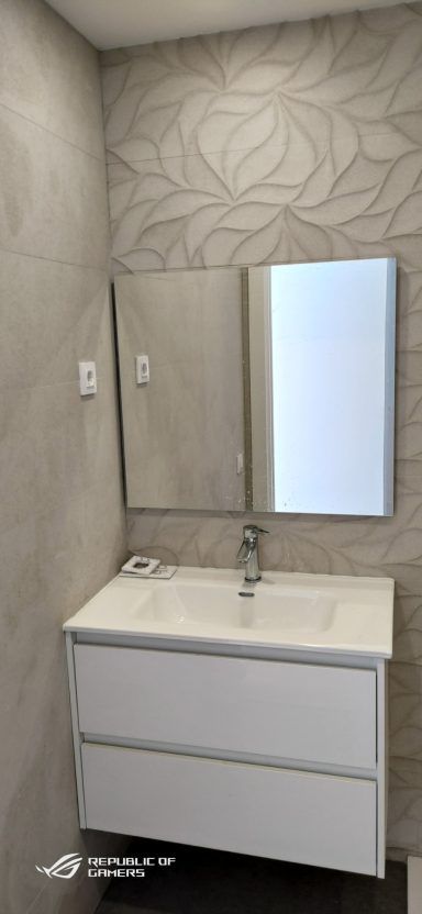 Un baño con lavabo, espejo y cajones.