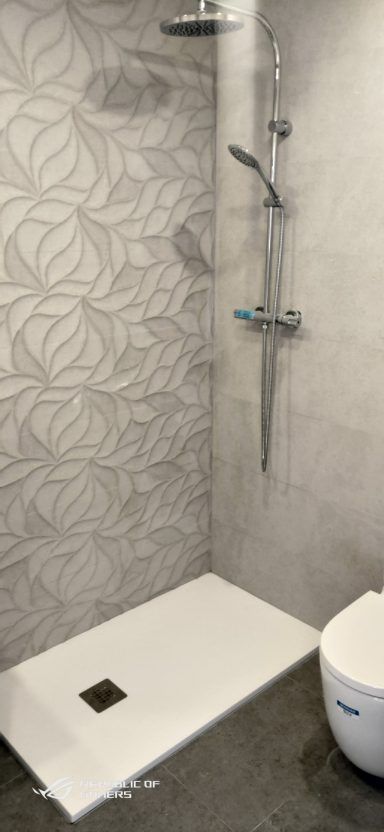 Un baño con ducha, inodoro y cabezal de ducha.