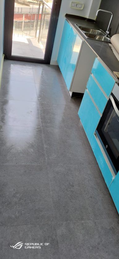 Una cocina con gabinetes azules y una encimera negra.