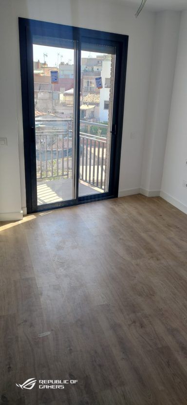 Una habitación vacía con un balcón y una puerta corrediza de vidrio.