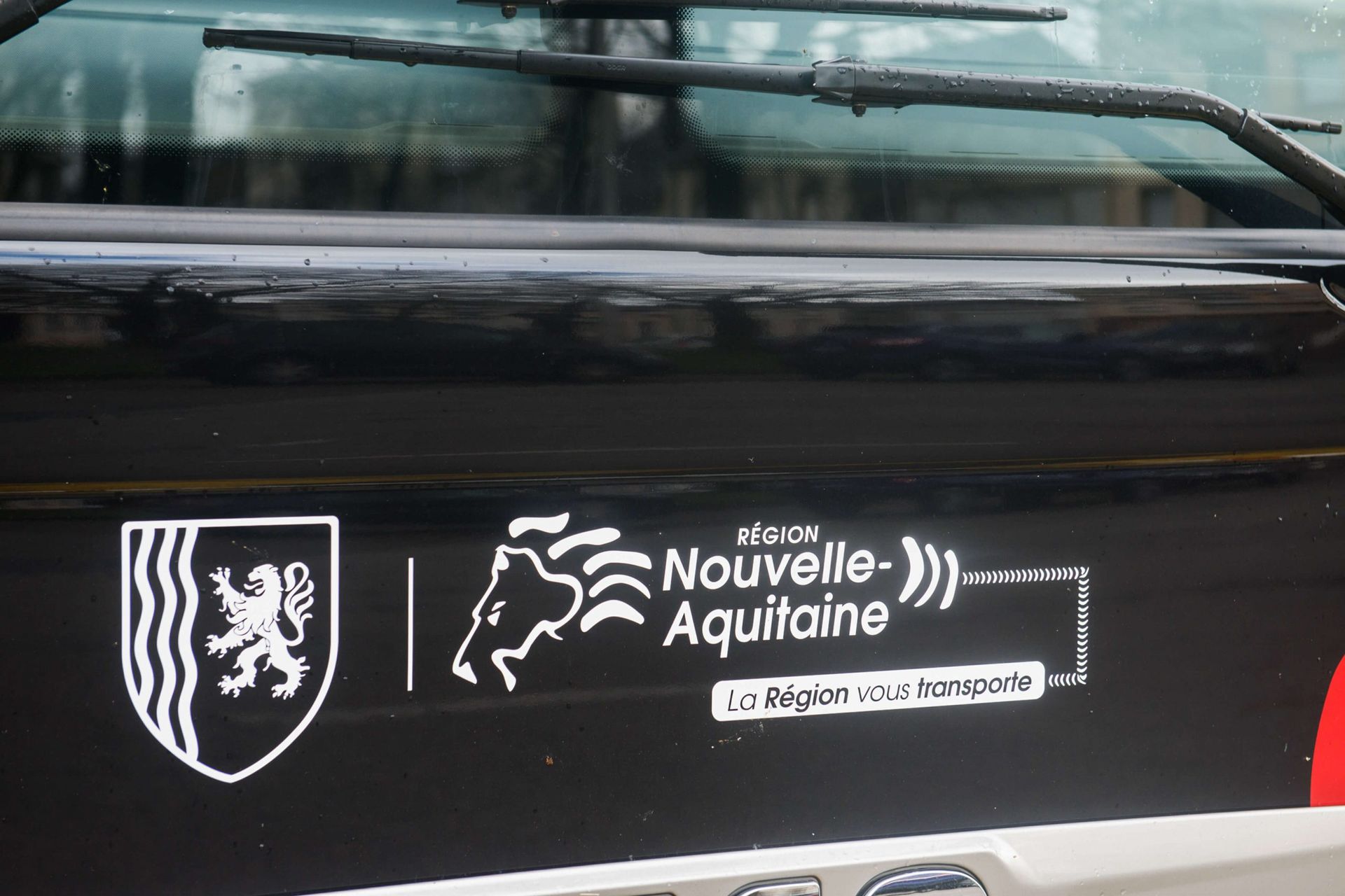 Black vehicle with Nouvelle-Aquitaine region logo: shield with lion, horse head, and text 