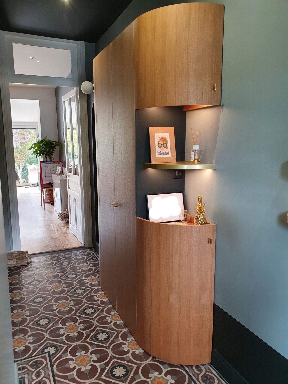 Entrée de maison avec un long couloir en arrière-plan et un petit meuble en bois au premier plan