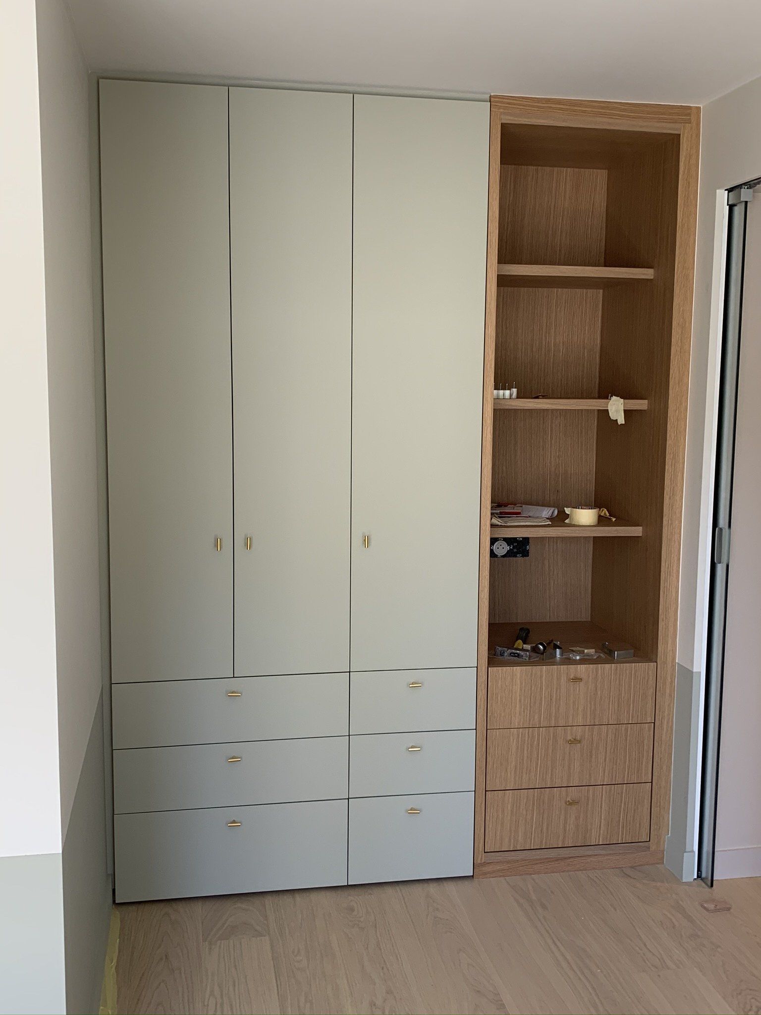 Grand et haut meuble blanc dont une porte ouverte laisse voir 3 étagères