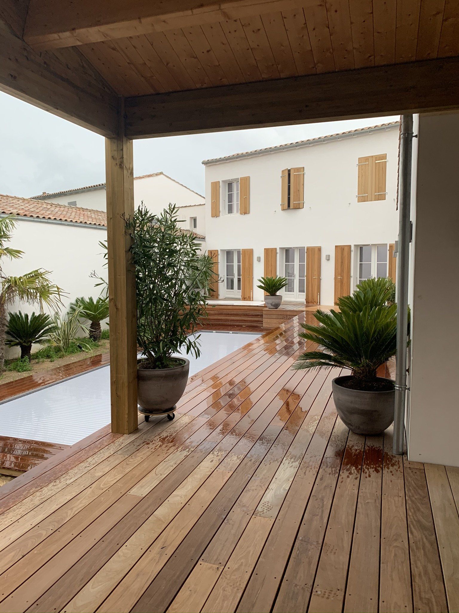 Terrasse en bois et piscine sous la pluie 