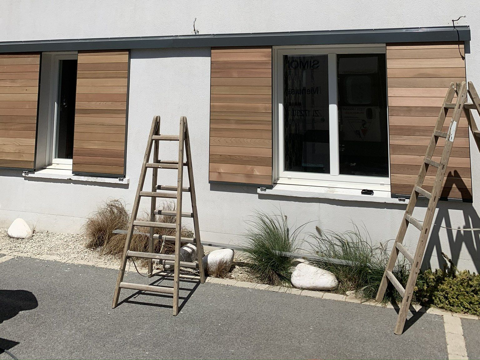 Escabeau devant une façade avec des volets bois ouverts