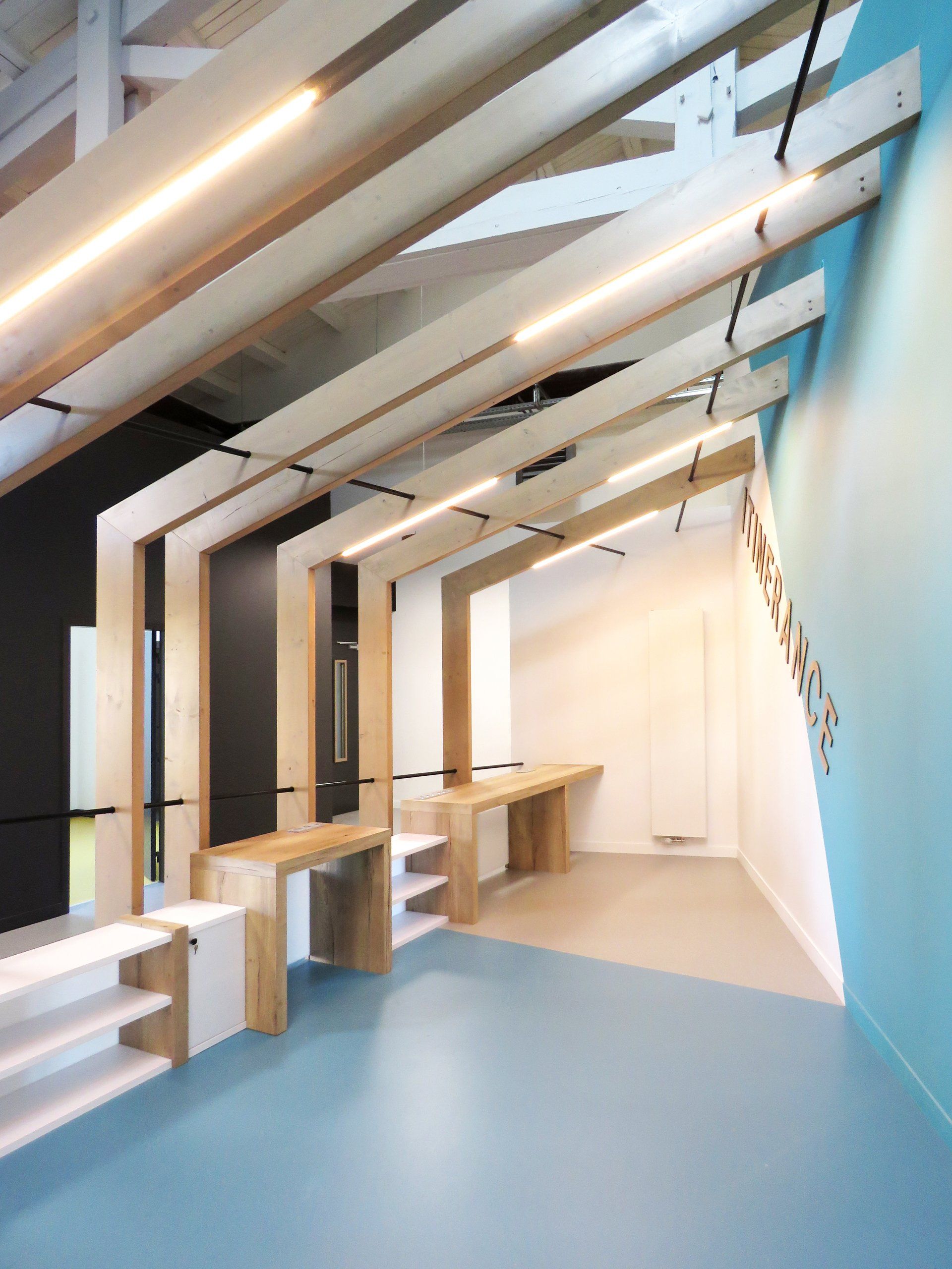 Demi-charpente avec des bancs en bois et un mur bleu à droite