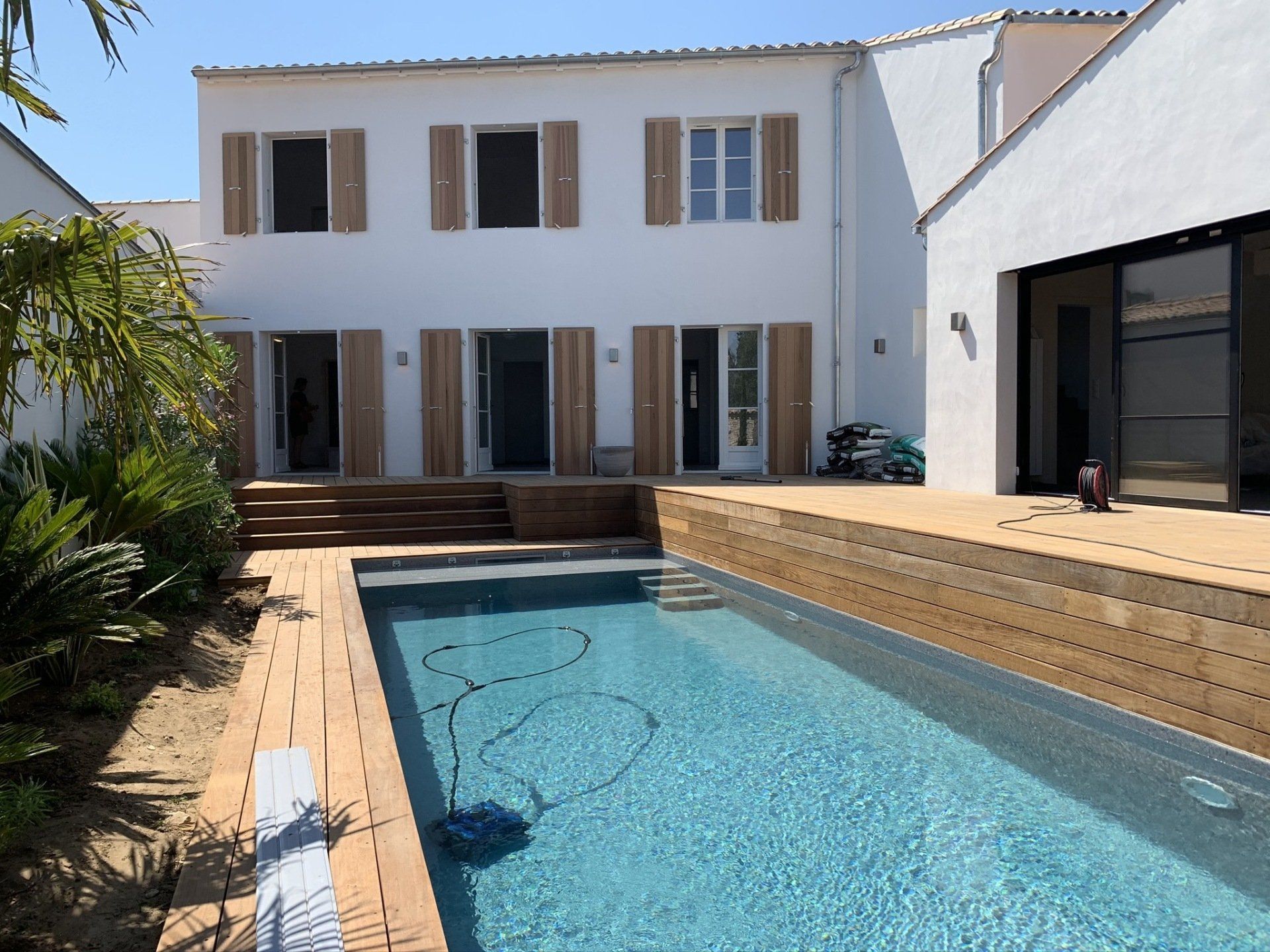 Piscine et tour de piscine en bois avec maison en arrière-plan
