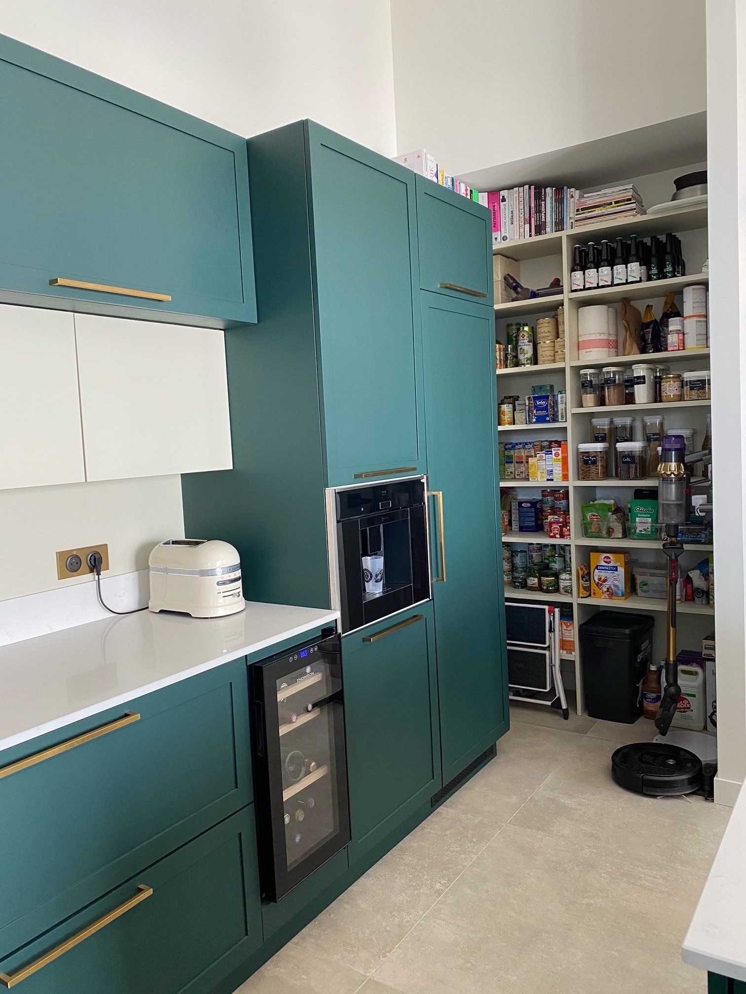 Angle d'une belle cuisine moderne avec un four et une grande étagère remplie de produits