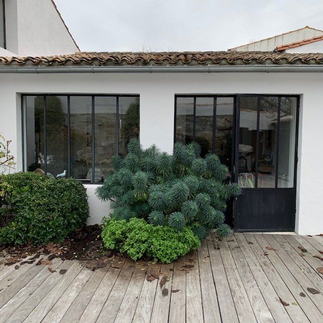 Double baie vitrée avec au premier plan des arbustes