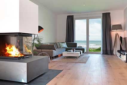 Ein Wohnzimmer mit Kamin und Blick auf das Meer.