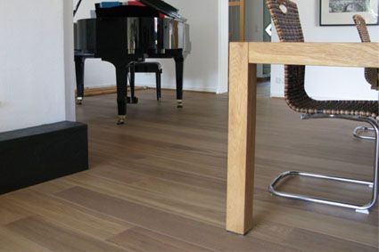 Ein Holztisch und Stühle in einem Wohnzimmer mit einem Klavier im Hintergrund