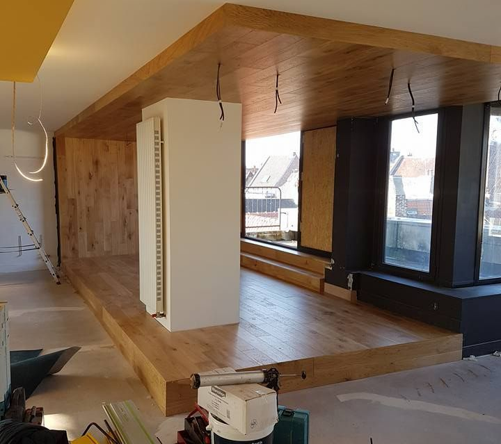 Un coin cuisine en cours d'aménagement avec de grandes fenêtres et des panneaux en bois au sol, aux murs et au plafond.