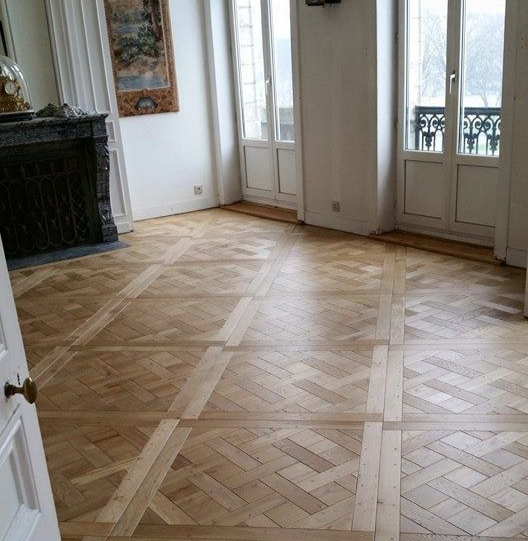 Une pièce lumineuse avec un parquet à chevrons et une cheminée.