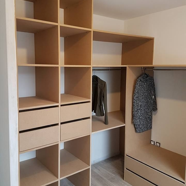 Une armoire ouverte en bois avec des étagères et une penderie.