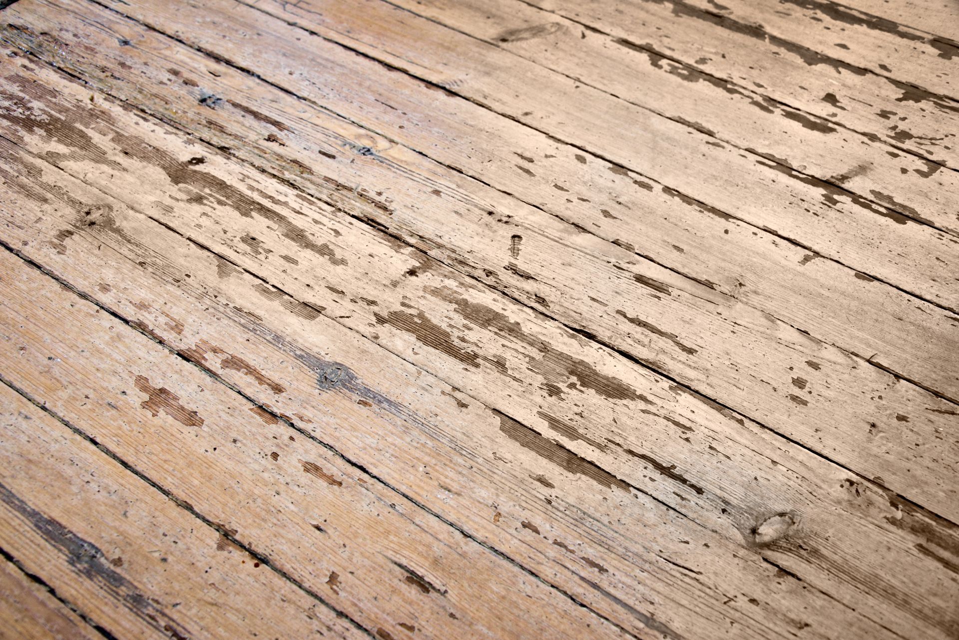 Un parquet en bois patiné, à la peinture écaillée et aux fissures sombres.