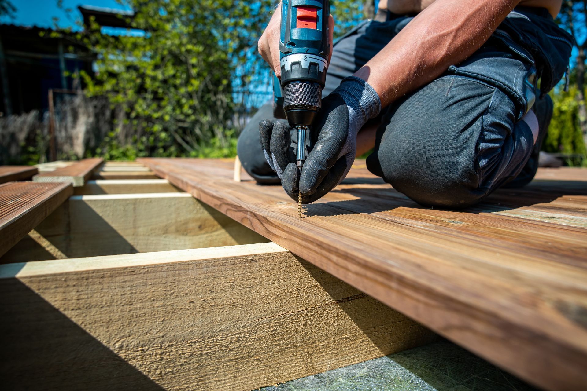Une personne perce une planche de terrasse en bois.